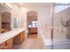 Bright bathroom with garden tub, glass-enclosed shower, and dual sinks overlooking bedroom at 7413 E Russet Sky Dr, Scottsdale, AZ 85266