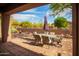 Covered patio with brick flooring, an outdoor dining table, chairs and desert landscaping at 7413 E Russet Sky Dr, Scottsdale, AZ 85266