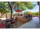 This backyard features gravel, concrete and an elevated patio with seating, shaded by a large tree at 7939 E Stonecliff Cir, Mesa, AZ 85207