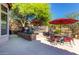 This backyard features a patio with multiple seating areas shaded by mature trees with desert landscaping at 7939 E Stonecliff Cir, Mesa, AZ 85207