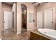 Well-lit bathroom boasts a tiled shower, tiled flooring, and a luxurious soaking tub at 7939 E Stonecliff Cir, Mesa, AZ 85207