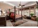Primary bedroom with a four-poster bed, patterned rug, and sitting area with bright natural light at 7939 E Stonecliff Cir, Mesa, AZ 85207