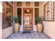 Inviting entryway with a wood door, large potted plants, decorative wall art, and sidelight windows at 7939 E Stonecliff Cir, Mesa, AZ 85207