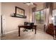 Home office featuring a dark wooden desk, neutral walls, and large window at 7939 E Stonecliff Cir, Mesa, AZ 85207