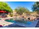 Inviting backyard pool features stone accents, with outdoor seating under a red umbrella at 7939 E Stonecliff Cir, Mesa, AZ 85207