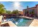 This backyard features a sparkling pool, patio, desert landscaping, seating and lovely architecture at 7939 E Stonecliff Cir, Mesa, AZ 85207