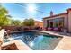 This backyard features a sparkling pool, patio, desert landscaping, seating and lovely architecture at 7939 E Stonecliff Cir, Mesa, AZ 85207