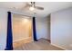 Cozy bedroom features a ceiling fan and a closet with sliding doors and custom blue curtains at 10557 W Louise Dr, Peoria, AZ 85383