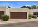 Two-car garage featuring a brown door, lush landscaping, and a paved driveway at 11633 N 40Th Way, Phoenix, AZ 85028