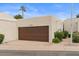 Two-car garage featuring a brown door, lush landscaping, and a paved driveway at 11633 N 40Th Way, Phoenix, AZ 85028
