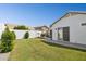 A backyard with a grass lawn, a white stucco wall, a grill, patio furniture and a sliding glass door at 13320 N 82Nd Dr, Peoria, AZ 85381