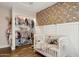 A well-organized Bedroom with a closet filled with clothes, a crib, and a floral wallpaper accent wall at 13320 N 82Nd Dr, Peoria, AZ 85381