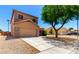 Two-story home with a two-car garage and desert landscaping complemented by a shade tree at 15427 W Port Au Prince Ln, Surprise, AZ 85379