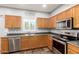 Modern kitchen featuring stainless steel appliances, oak cabinets, tile flooring, and gray countertops at 15427 W Port Au Prince Ln, Surprise, AZ 85379
