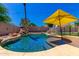 Sparkling pool with slide, rock waterfall feature, and umbrella providing shade for backyard fun at 15427 W Port Au Prince Ln, Surprise, AZ 85379