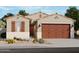 Inviting single story home featuring a two car garage, neutral stucco facade, shuttered windows and desert landscaping at 16001 W Bronco Trl, Surprise, AZ 85387