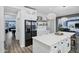 A stylish kitchen featuring a large island, stainless steel appliances, white cabinetry, and modern lighting at 18429 W Mauna Loa Ln, Surprise, AZ 85388