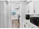 A modern kitchen with a breakfast nook and hallway featuring white cabinets, stainless steel appliances, and contemporary lighting at 18429 W Mauna Loa Ln, Surprise, AZ 85388