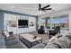 A comfortable living room with a ceiling fan, plush seating, built-in shelving, and natural light from the windows at 18429 W Mauna Loa Ln, Surprise, AZ 85388