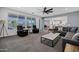 An inviting living room with a ceiling fan, plush seating, coffee table, and views of the backyard and kitchen at 18429 W Mauna Loa Ln, Surprise, AZ 85388