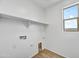 Functional laundry room with washer hookups, shelf, and light tile flooring at 18950 W Stella Ave, Waddell, AZ 85355
