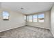 A bright bedroom with carpeted floors, neutral walls and multiple windows that let in plenty of natural light at 19026 W Stella Ave, Waddell, AZ 85355