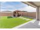 Backyard features artificial turf, pavers, and outdoor lounge area with pergola cover and brick perimeter wall at 19407 W Pierson St, Litchfield Park, AZ 85340