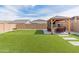 Landscaped backyard with artificial turf, patio lounge area with TV, plus brick perimeter wall and swing set at 19407 W Pierson St, Litchfield Park, AZ 85340