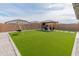 Spacious backyard with artificial turf, a swing set, an outdoor pergola with patio furniture, and a brick wall at 19407 W Pierson St, Litchfield Park, AZ 85340
