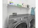 Laundry room equipped with front loading washer and dryer, along with a shelf for storing cleaning and laundry supplies at 19806 W Marshall Ave, Litchfield Park, AZ 85340