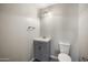 Bathroom with sink, vanity, toilet, gray walls, laminate flooring, and a three-bulb vanity light fixture at 22926 W Yavapai St, Buckeye, AZ 85326