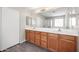Bathroom with double sink, wooden vanity, a mirror, laminate flooring, and a closet at 22926 W Yavapai St, Buckeye, AZ 85326