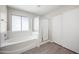 Bathroom featuring a bathtub, shower, laminate flooring, gray walls, a window, and a sliding door closet at 22926 W Yavapai St, Buckeye, AZ 85326