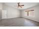 Bedroom featuring gray walls, laminate flooring, ceiling fan, window with a view, and a door at 22926 W Yavapai St, Buckeye, AZ 85326