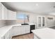 Kitchen featuring white cabinets, stainless steel dishwasher, black sink, window, and light-colored laminate flooring at 22926 W Yavapai St, Buckeye, AZ 85326
