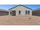 Back exterior view of the home with stucco, dark roof, rock landscaping, and double-pane windows for beauty and efficiency at 25235 N 183Rd Dr, Wittmann, AZ 85361