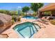Community hot tub and pool with a rock waterfall and comfortable lounge chairs around pool at 25555 N Windy Walk Dr # 64, Scottsdale, AZ 85255