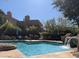 Community pool featuring clear blue water, lush greenery, and lounge chairs with umbrellas at 25555 N Windy Walk Dr # 64, Scottsdale, AZ 85255