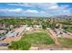 Aerial view of a rural property highlighting a lush green field, outbuildings, and residences against a scenic mountain backdrop at 26232 S Lemon Ave, Queen Creek, AZ 85142