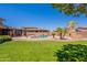 Expansive backyard featuring a pool, lush lawn, desert landscaping, and outdoor fireplace, ideal for outdoor living at 30277 N 125Th Ln, Peoria, AZ 85383