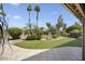 A beautifully landscaped backyard with a pond, mature trees, and lush green grass at 3394 N 147Th Ln, Goodyear, AZ 85395