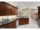 Kitchen with dark wood cabinets, a stainless-steel dishwasher, granite counter-tops, and a black sink at 3394 N 147Th Ln, Goodyear, AZ 85395