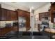 Modern kitchen with stainless steel appliances, dark cabinetry, granite countertops, and sleek black sink at 3394 N 147Th Ln, Goodyear, AZ 85395