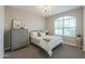 Cozy bedroom with plush carpet, a decorative light fixture, and a large window at 37903 W San Clemente St, Maricopa, AZ 85138