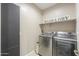 Modern laundry room with a front-loading washer and dryer set, a shelf, and a 'Wash & Dry' sign at 37903 W San Clemente St, Maricopa, AZ 85138