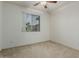 A neutral-colored bedroom features a carpeted floor, ceiling fan and a window with coverings at 42310 W Fountainhead St, Maricopa, AZ 85138