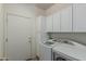 Bright laundry room with cabinets, appliances, and door at 42310 W Fountainhead St, Maricopa, AZ 85138