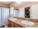 Bathroom with dual sinks, a large mirror, a window, and a bathtub with a shower at 7169 S Dodane Ct, Gilbert, AZ 85298