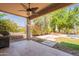 Covered patio boasts ceiling fan and tile flooring, overlooking a green yard and a pool at 7169 S Dodane Ct, Gilbert, AZ 85298