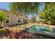 Backyard showcases sparkling pool, mature trees, wrought iron furniture, and exterior of home at 7169 S Dodane Ct, Gilbert, AZ 85298